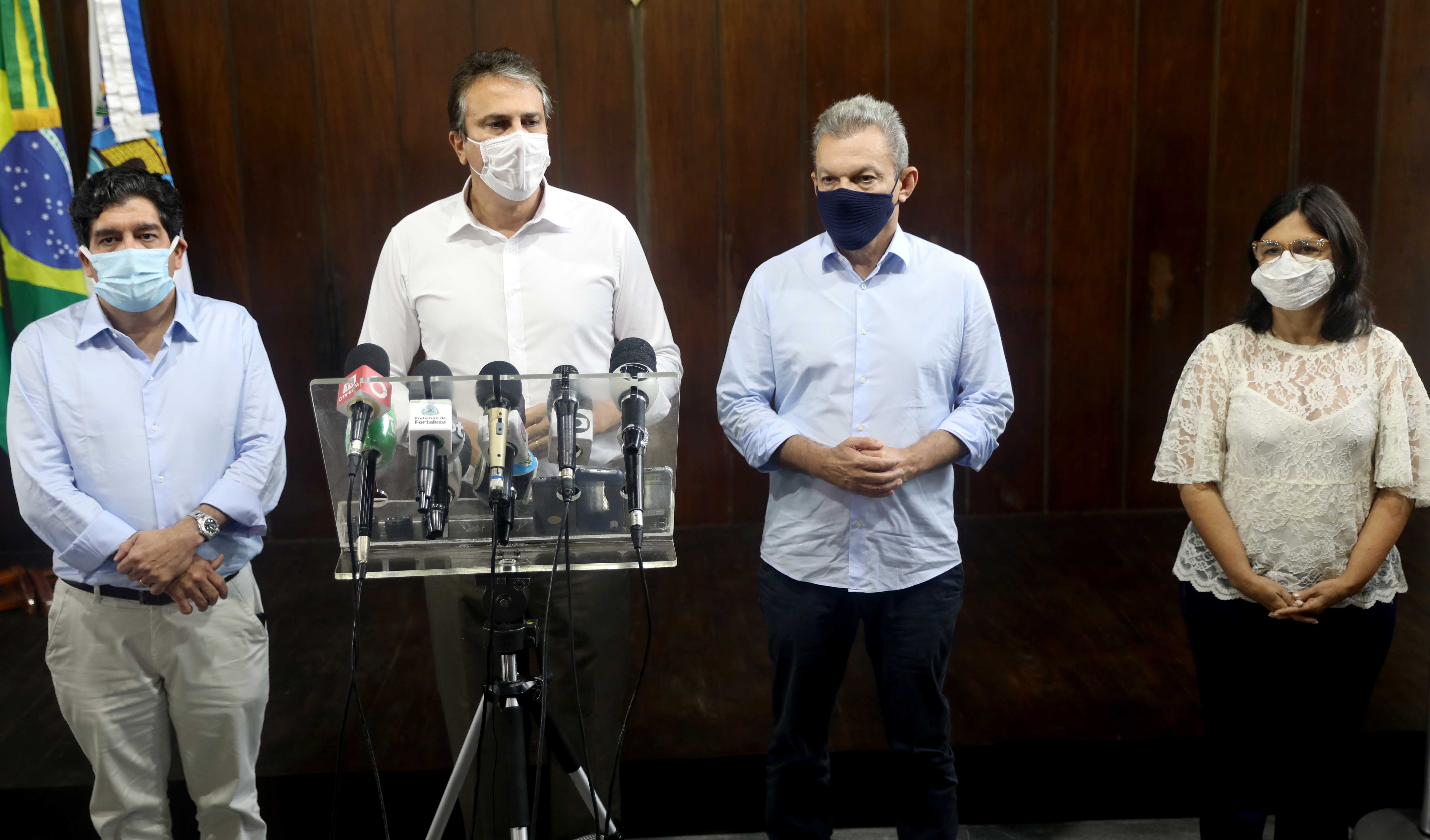 Dr. Cabeto, Camilo Santana, José Sarto e Ana Estela Leite, todos em pé lado a lado e governador falando em frente a púlpito com microfones